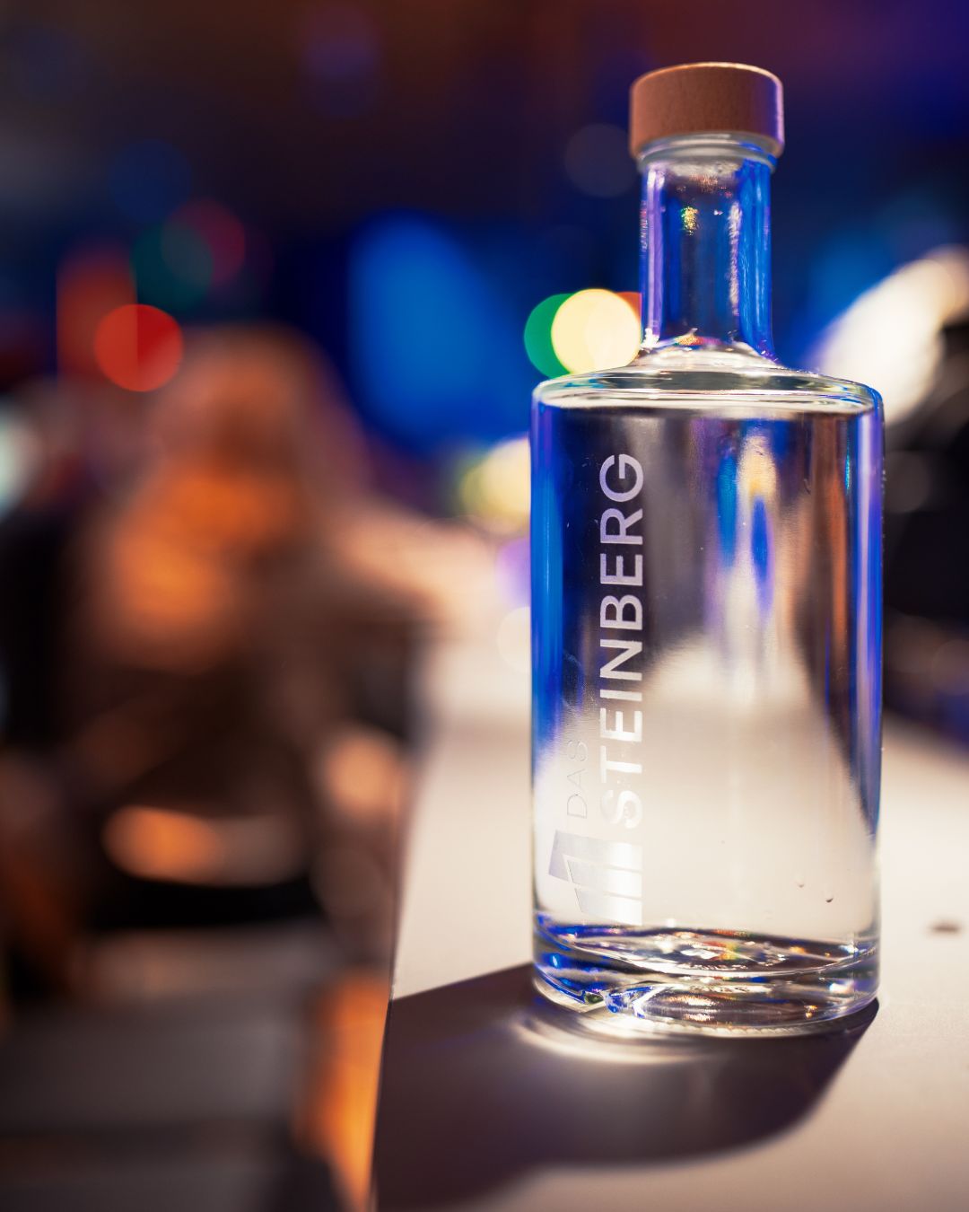 Eine Flasche mit dem Das Steinberg Gin vor verschwommenem Hintergrund an der Bar.